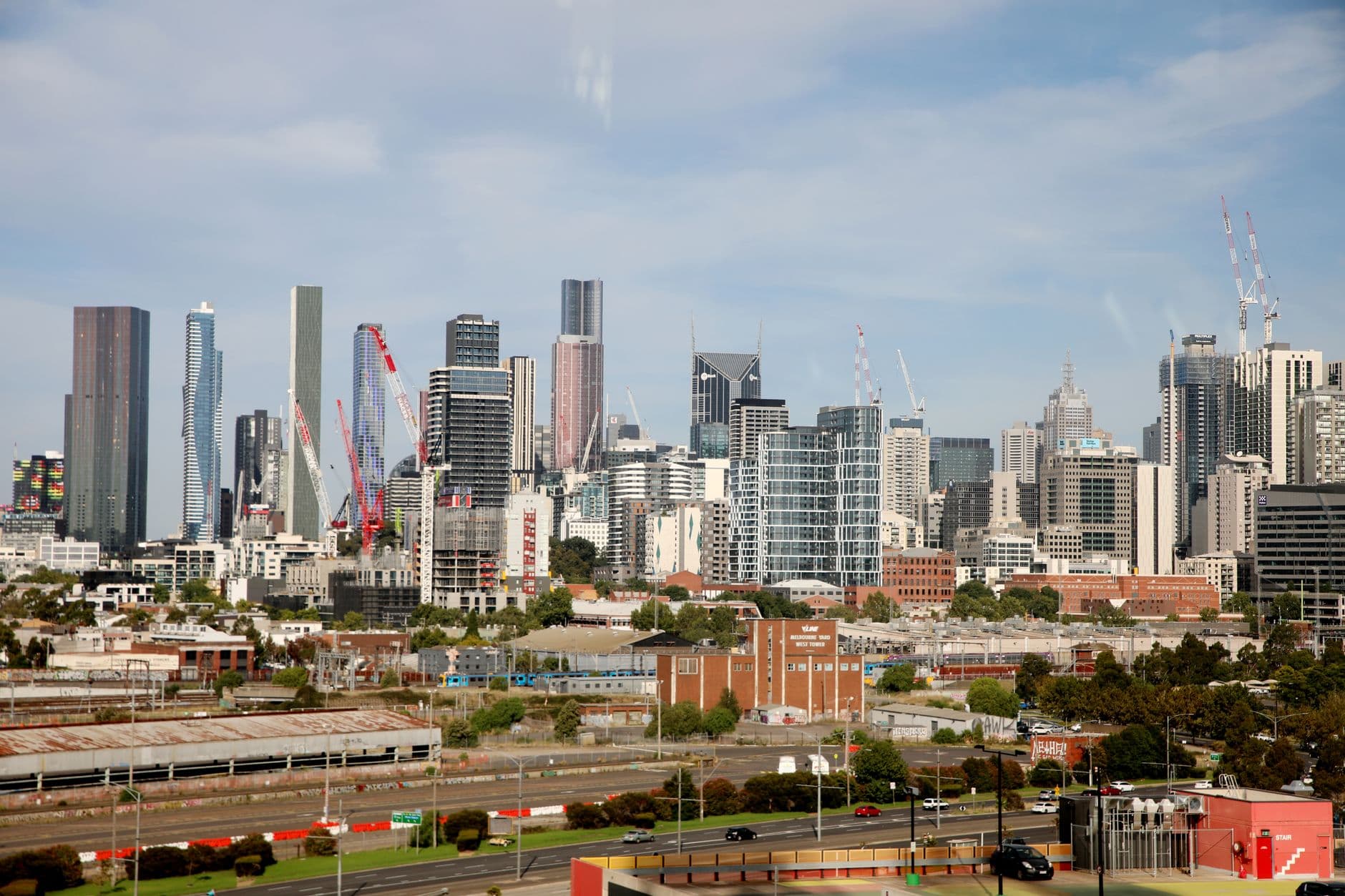 View of Melbourne's skyline featuring tall skyscrapers and construction cranes under a clear sky.